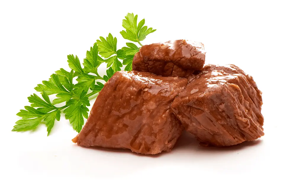 Pile of cooked beef cubes with some parsley leaves