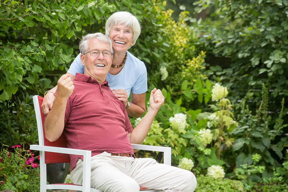 An romantic elderly couple sitting outside and having fun together in a garden